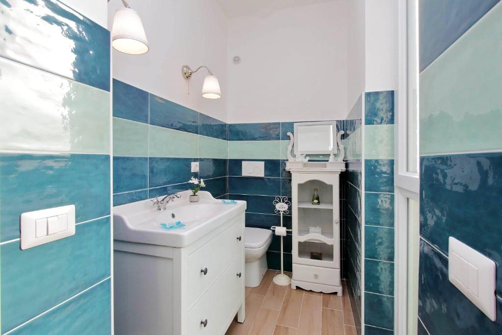 Bathroom with teal and green tiles, white fixtures