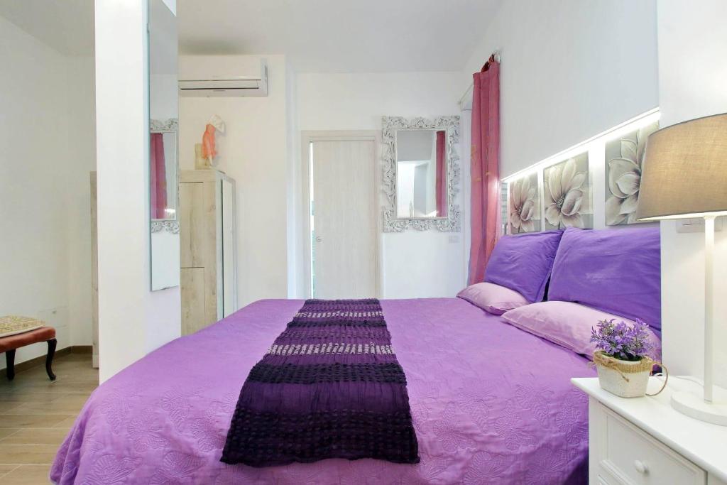 Bedroom with purple bedding, white headboard, floral artwork