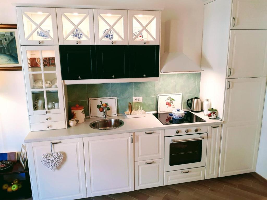 Kitchen with white cabinets, green tile backsplash